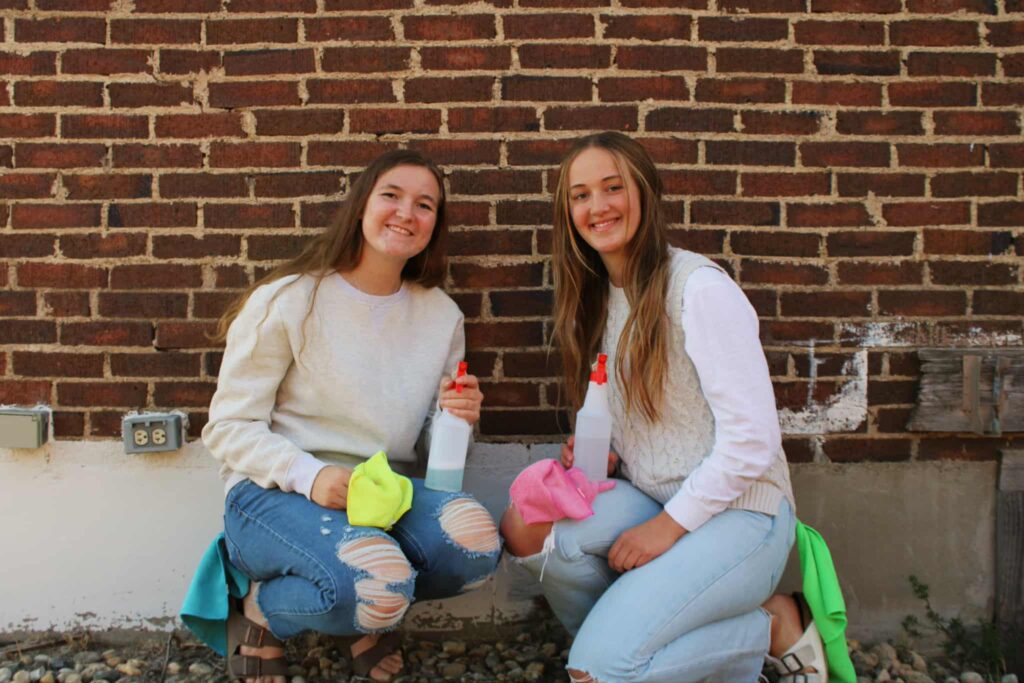 Aliyah and I with our cleaning supplies with a brick background
